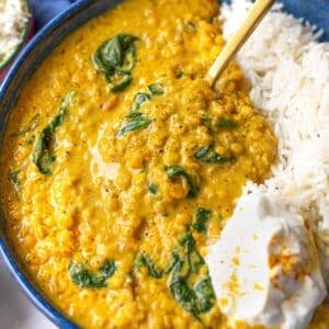 Creamy bowl of easy red lentil dal with basmati rice and yogurt on top.