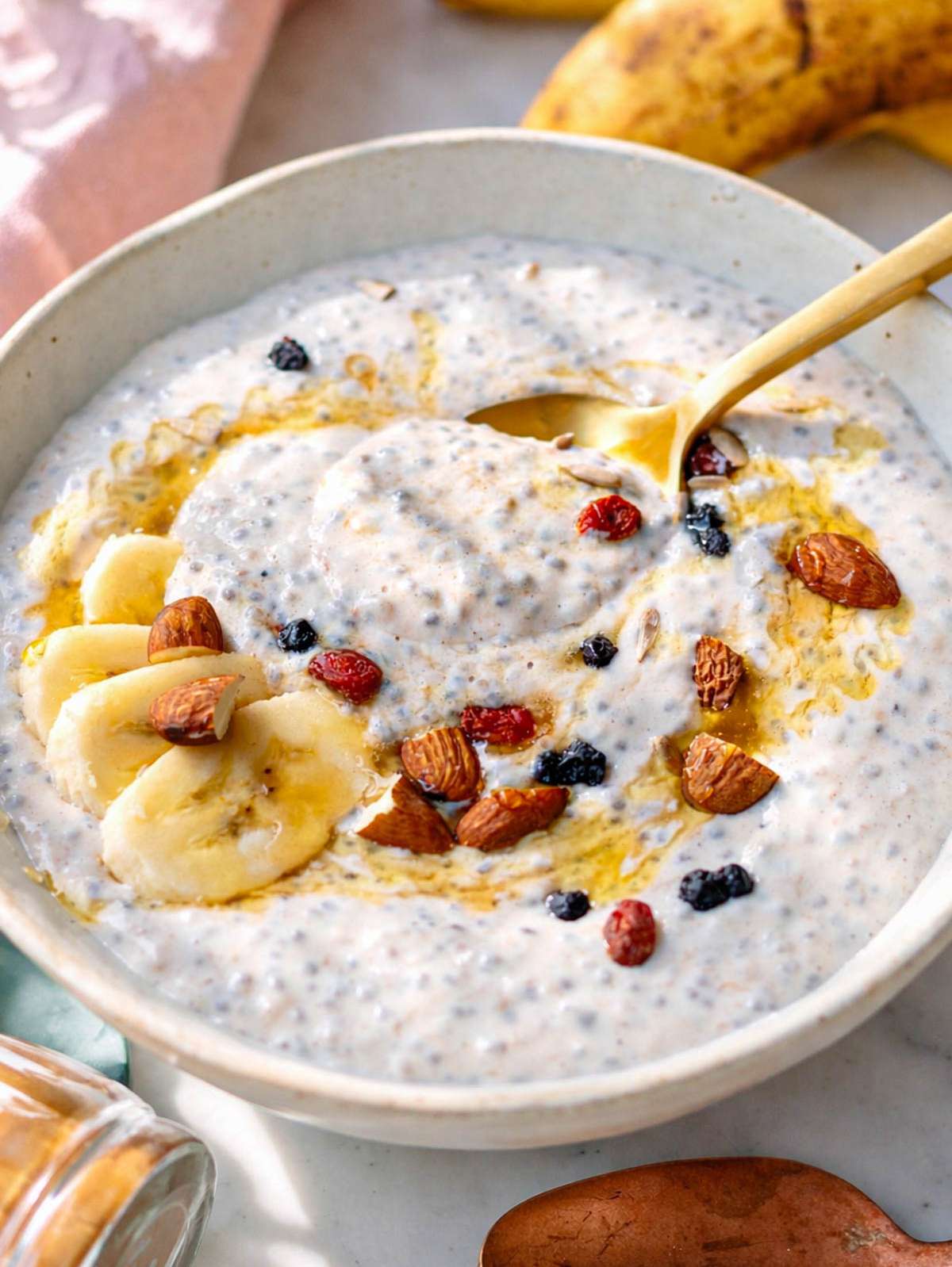 Finished banana chia pudding in a bowl topped with fresh banana, nuts, and honey.