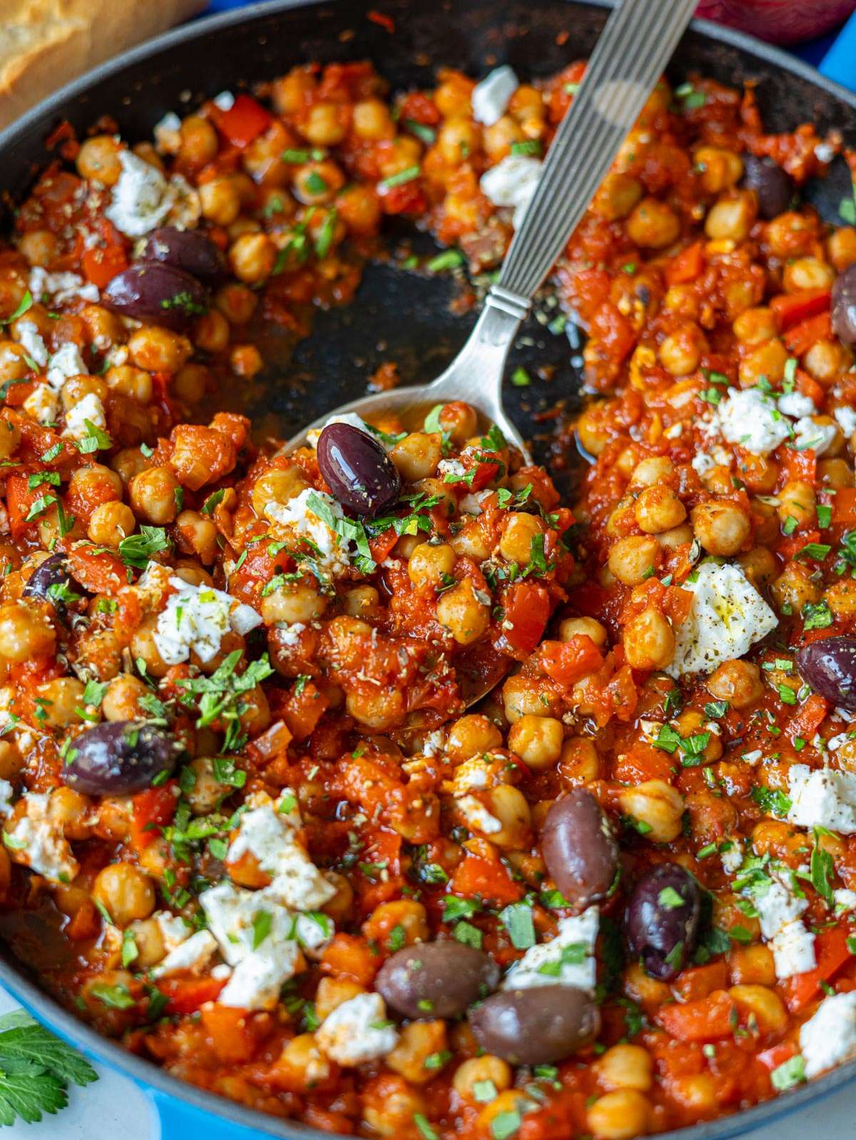 Finished chickpea shakshuka served in a skillet with feta, herbs, and Kalamata olives on top