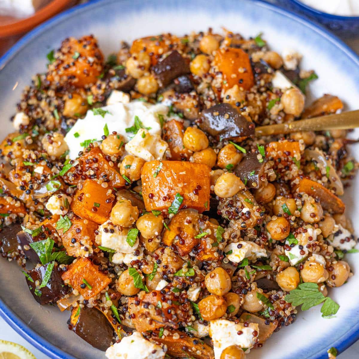 Finished chickpea shawarma bowl on the table with lemon wedges and herbs, ready to eat.