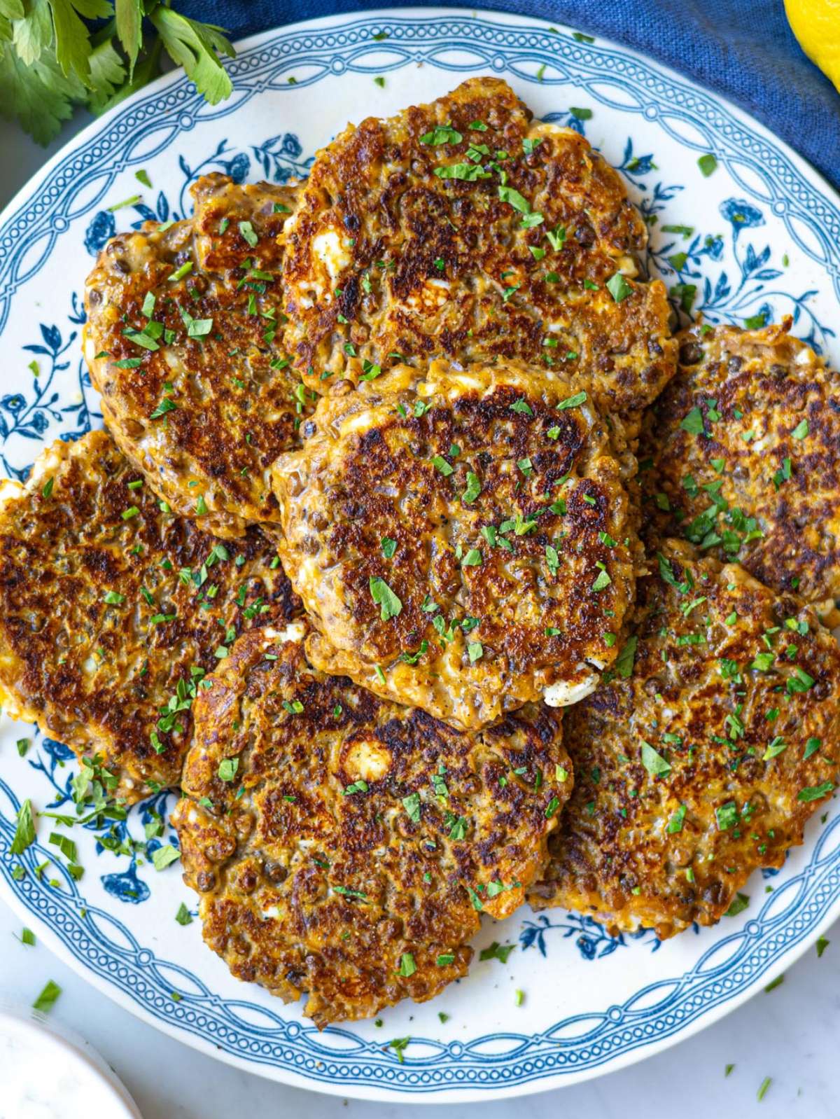 Finished lentil sweet potato patties stacked on plate topped with parsley.
