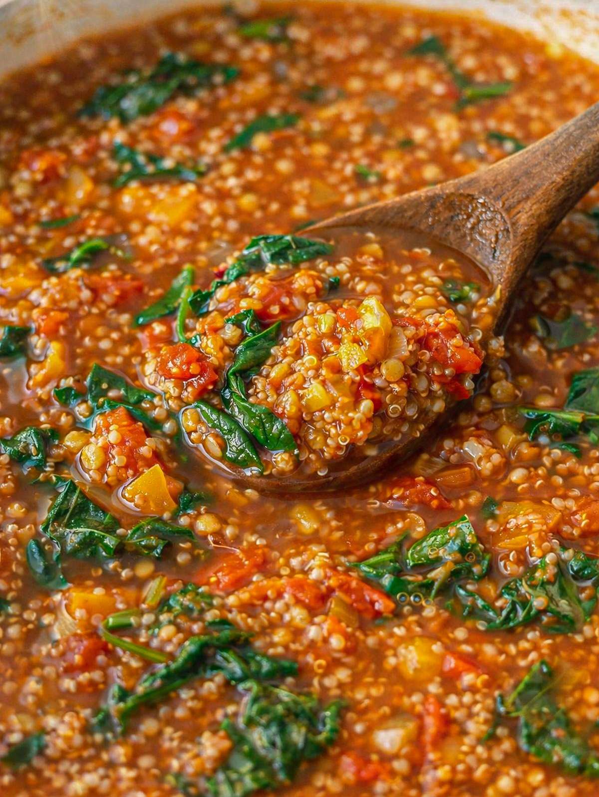 Finished quinoa vegetable soup in a bowl, hearty and colorful with vegetables and greens.
