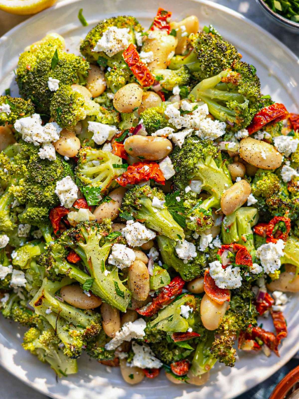 Finished roasted broccoli salad served on a platter with butter beans, feta, and lemon dressing.