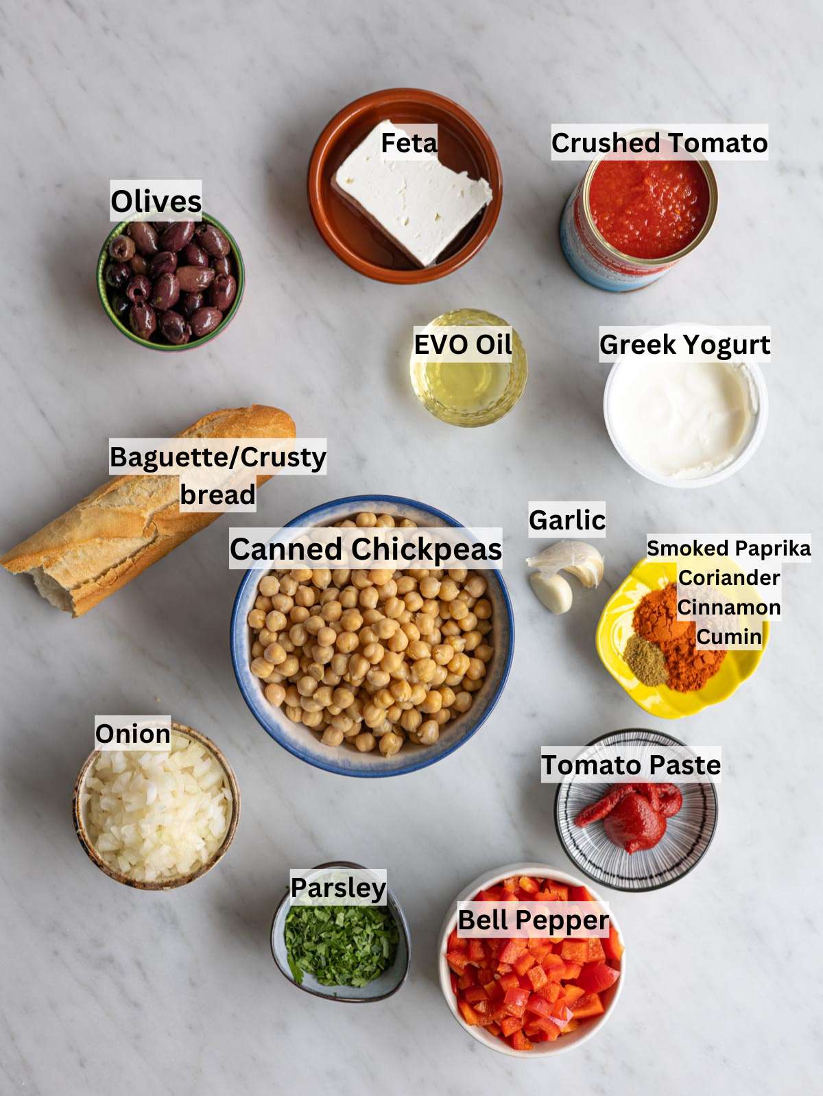 Ingredients for chickpea shakshuka laid out with chickpeas, tomatoes, spices, onion, and olive oil.