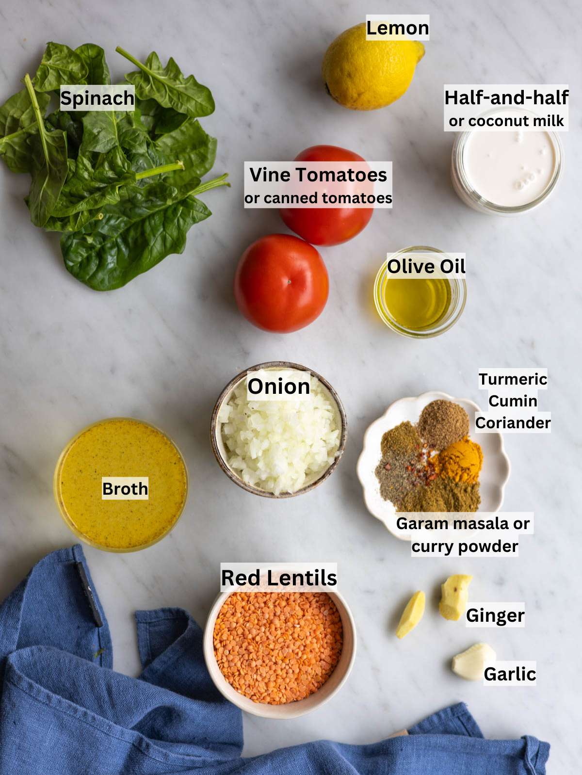Ingredients for red lentil dal arranged on a wooden table with spices, lentils, and fresh spinach.