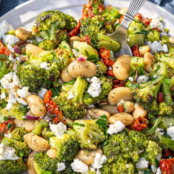 Roasted broccoli salad with butter beans and feta served family-style on a simple table.
