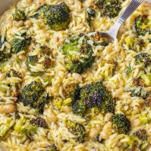 Skillet with creamy lemony broccoli orzo with white beans and black pepper.