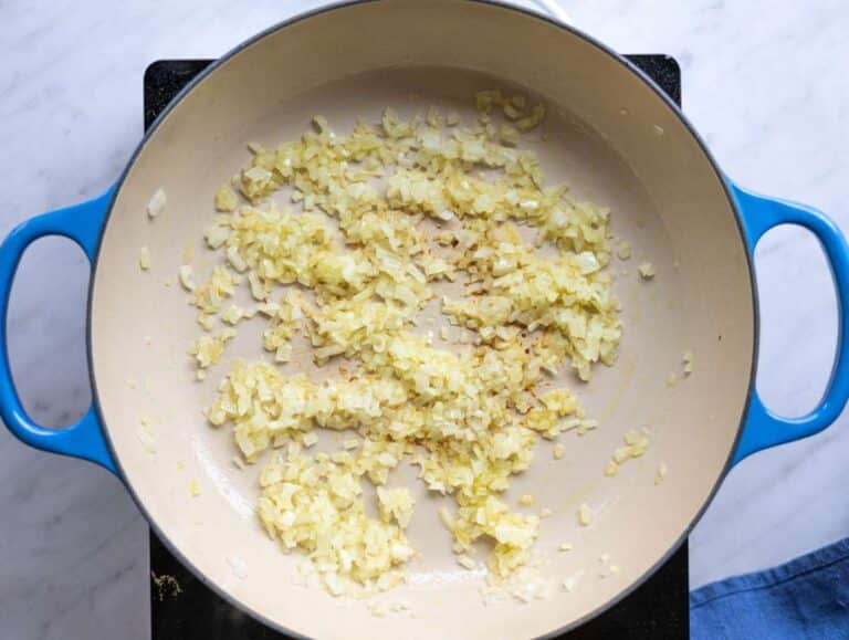 Step 1 Chopped onion sautéing in olive oil in a wide pot on the stove.