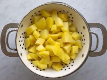 Step 1 Par-boiled potatoes steaming off in a colander.