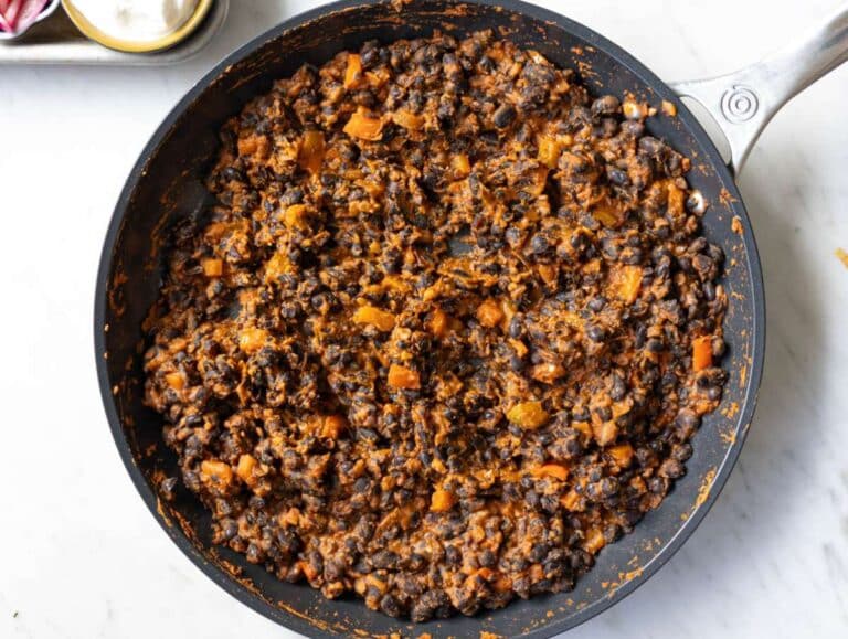 Step 3 Black beans simmering and lightly mashed in a skillet with thick savory sauce.