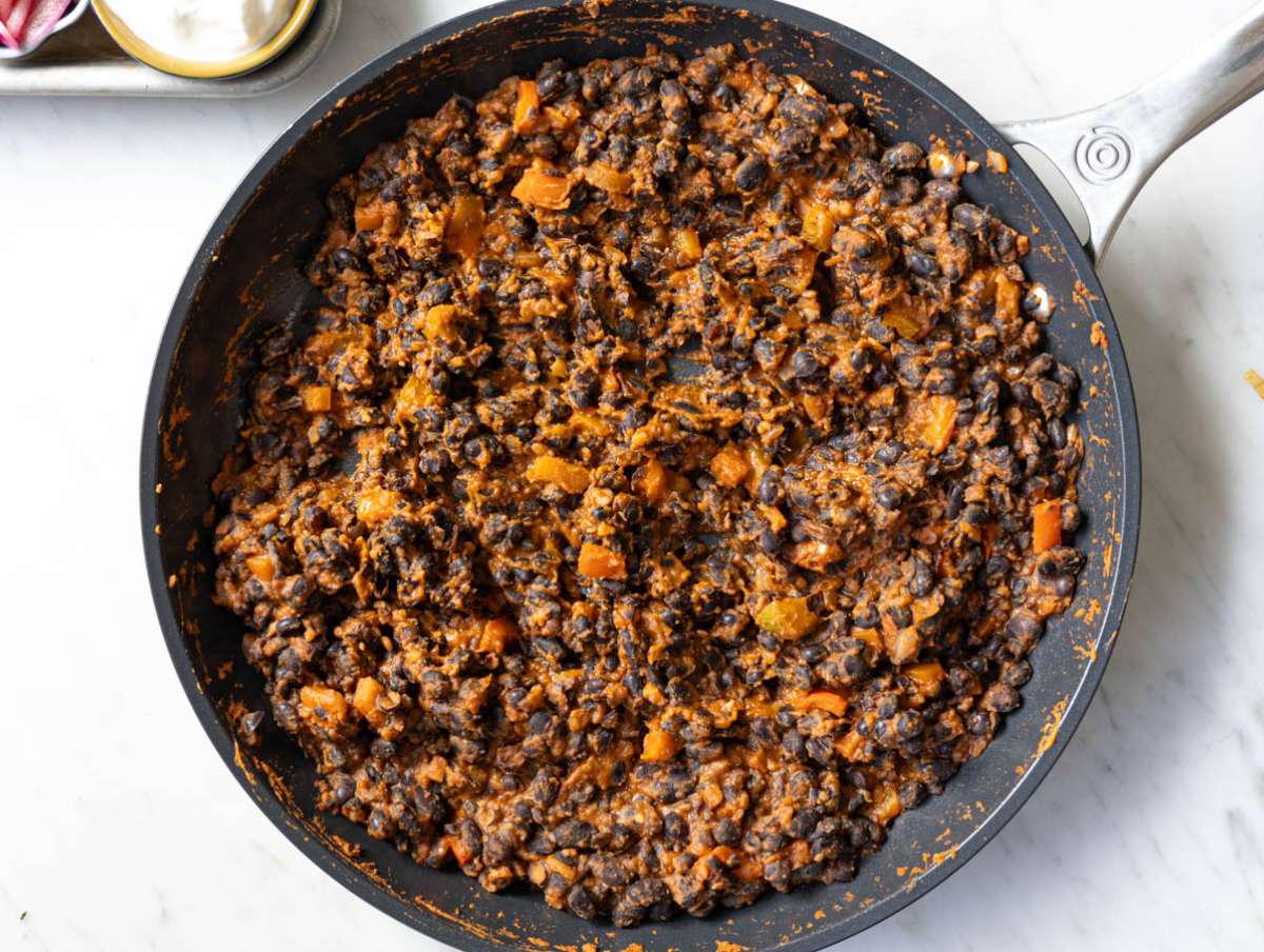 Step 3 Black beans simmering and lightly mashed in a skillet with thick savory sauce.