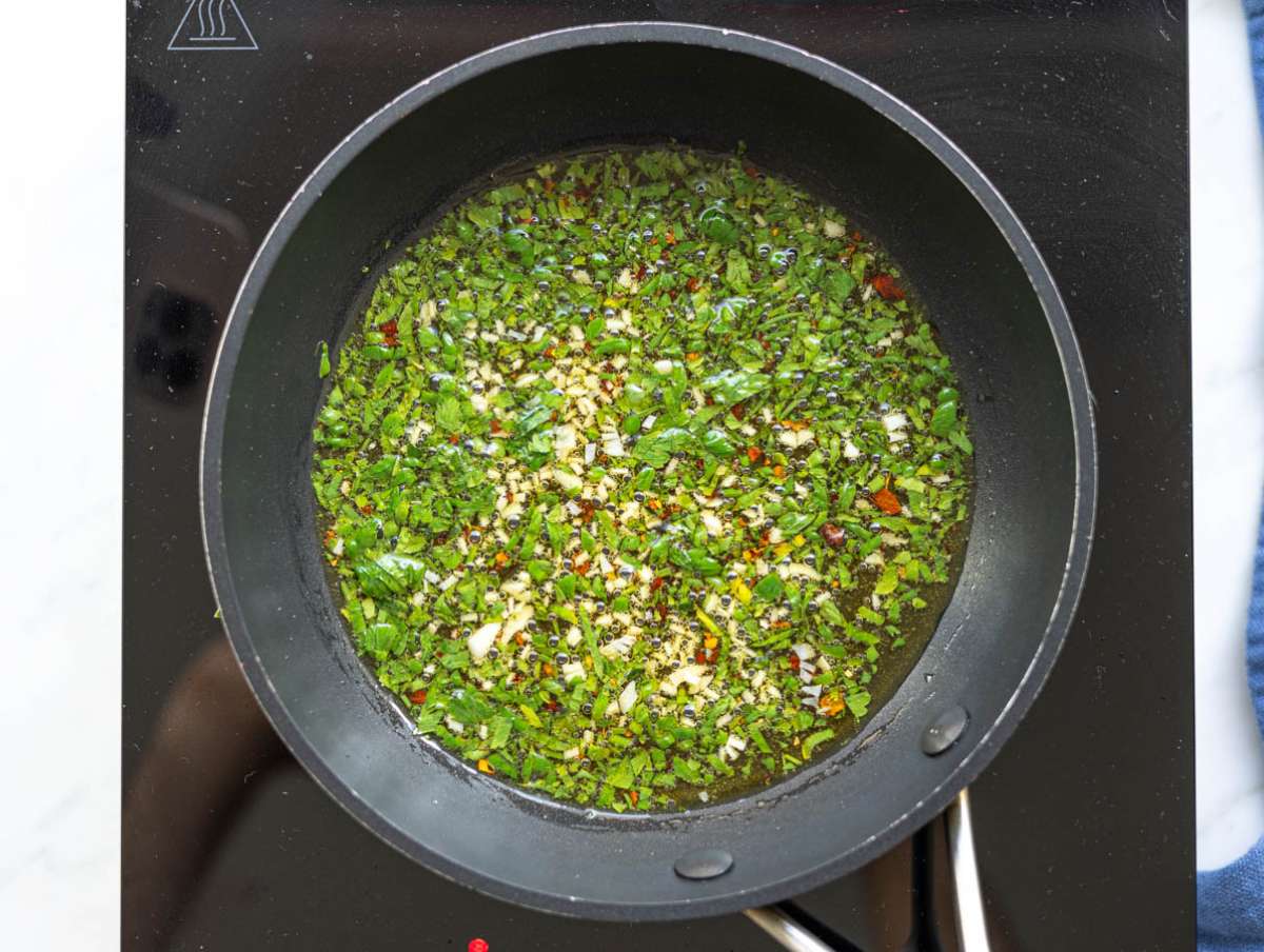 Step 3 Garlic chili oil gently sizzling in a small pan with fresh herbs.