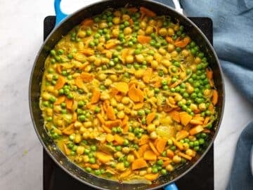 Step 4 Chickpeas, peas, and carrots simmering in the skillet with broth and spices.