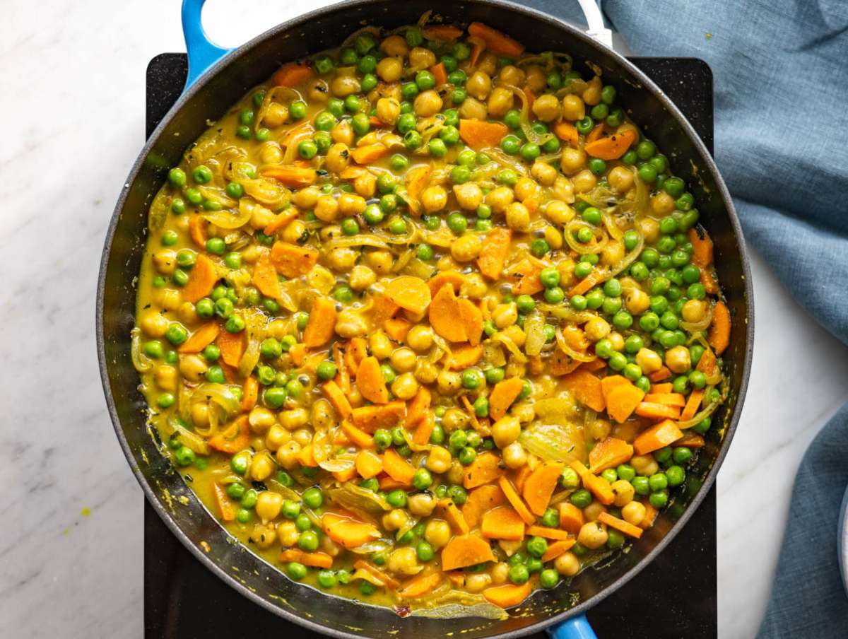 Step 4 Chickpeas, peas, and carrots simmering in the skillet with broth and spices.