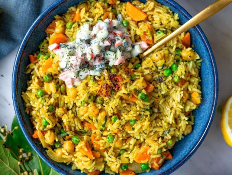 Step 6 Easy vegetable biryani rice served in a bowl with a dollop of raita, lemon juice, and a golden spoon.