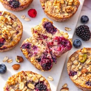 Baked oatmeal cups on marble table showing moist berry-filled center.