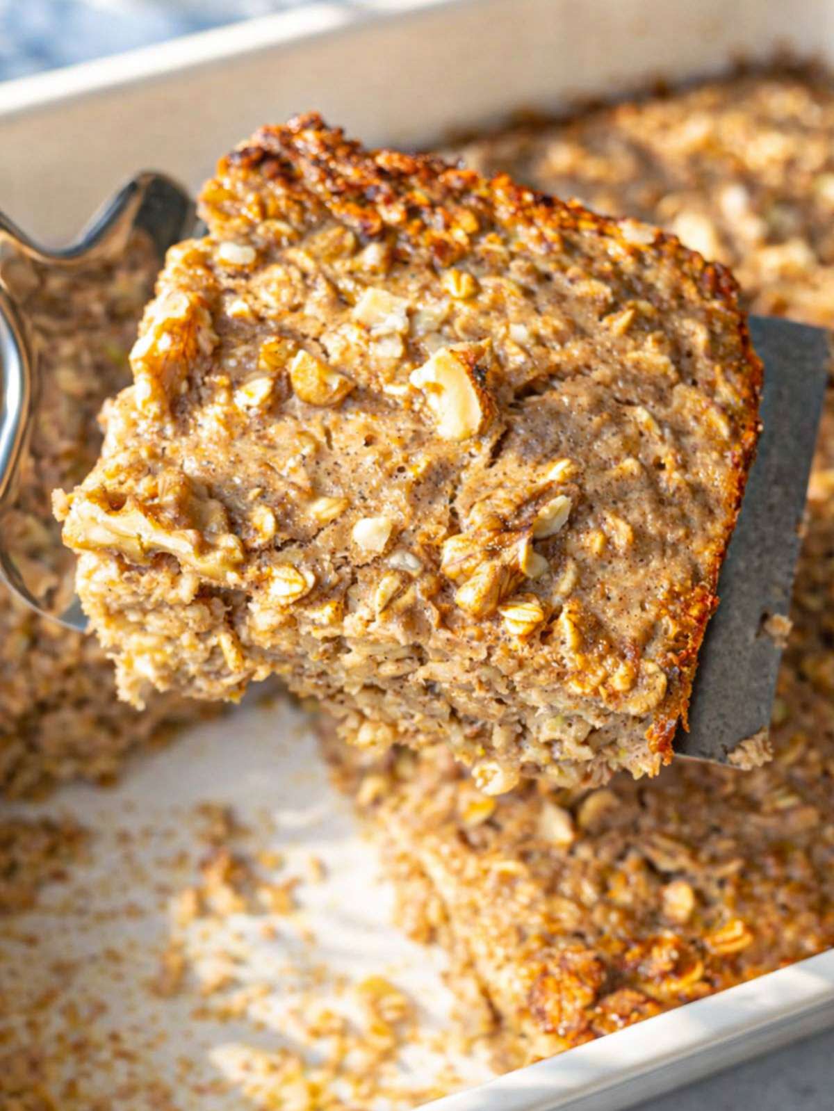 Banana baked oatmeal in ceramic dish on wooden table in natural light.