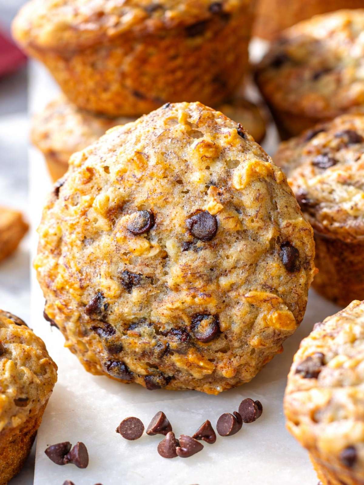 Banana chocolate chip muffins on marble table golden and lightly domed.