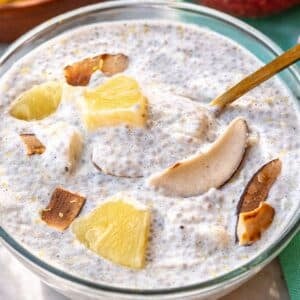 Bowl of pineapple chia pudding on sunlit table with spoon.