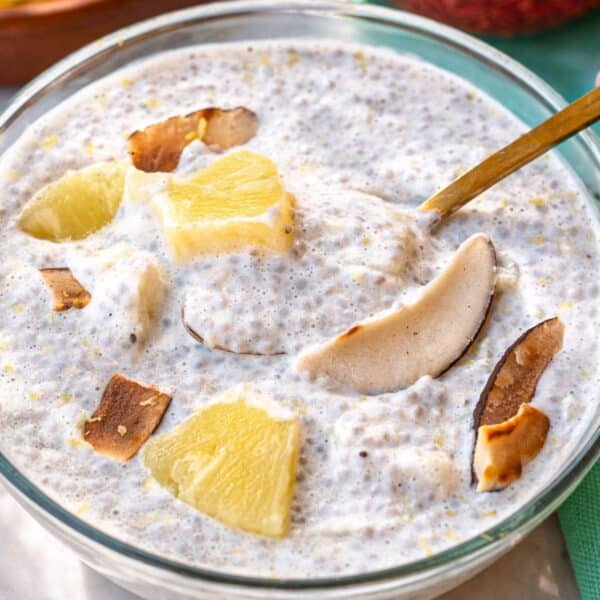Bowl of pineapple chia pudding on sunlit table with spoon.