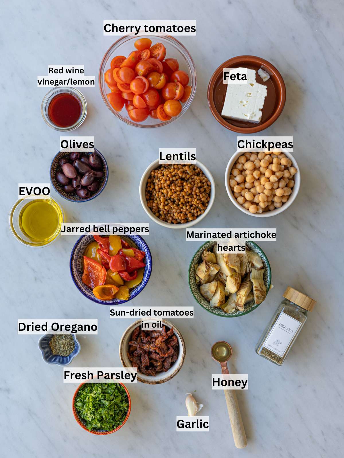 Chickpeas, lentils, roasted peppers, artichokes, olives, tomatoes, feta, parsley on table.