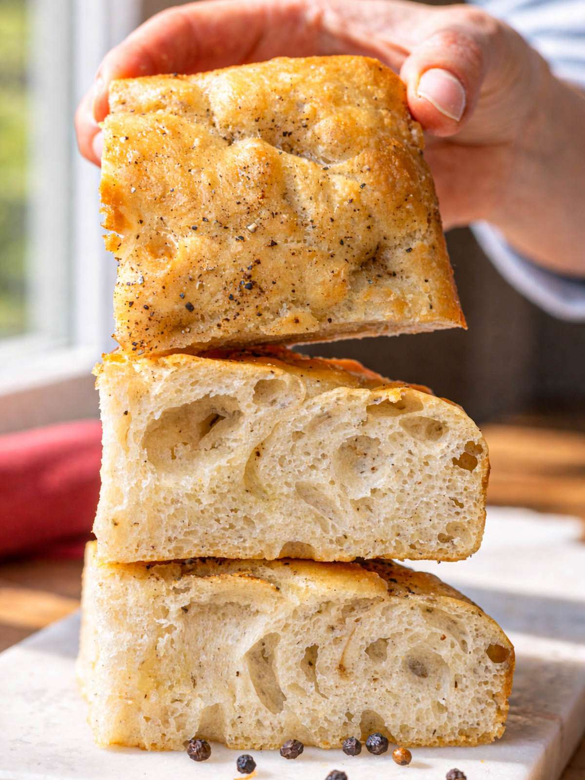 Close-up of black pepper focaccia crumb showing airy interior and crisp, dimpled surface.