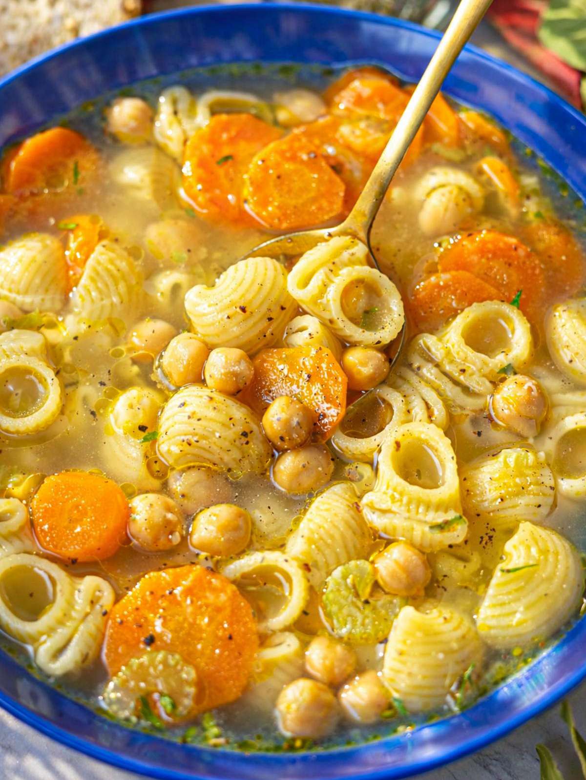 Close-up of chickpea noodle soup showing tender pasta, chickpeas, and herbs in the broth.