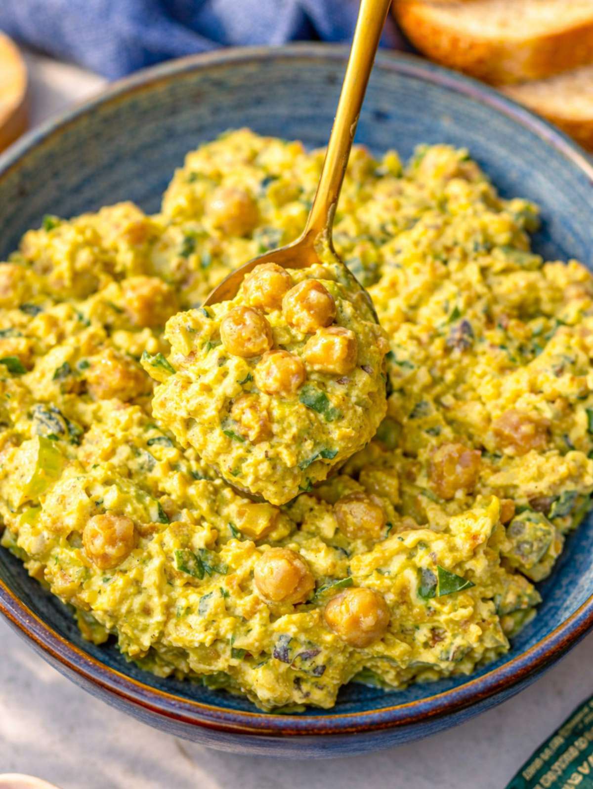Close up of creamy chickpea salad with visible celery and herbs.