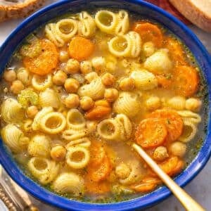 Cozy bowl of chickpea noodle soup served hot with olive oil and grated Parmesan.
