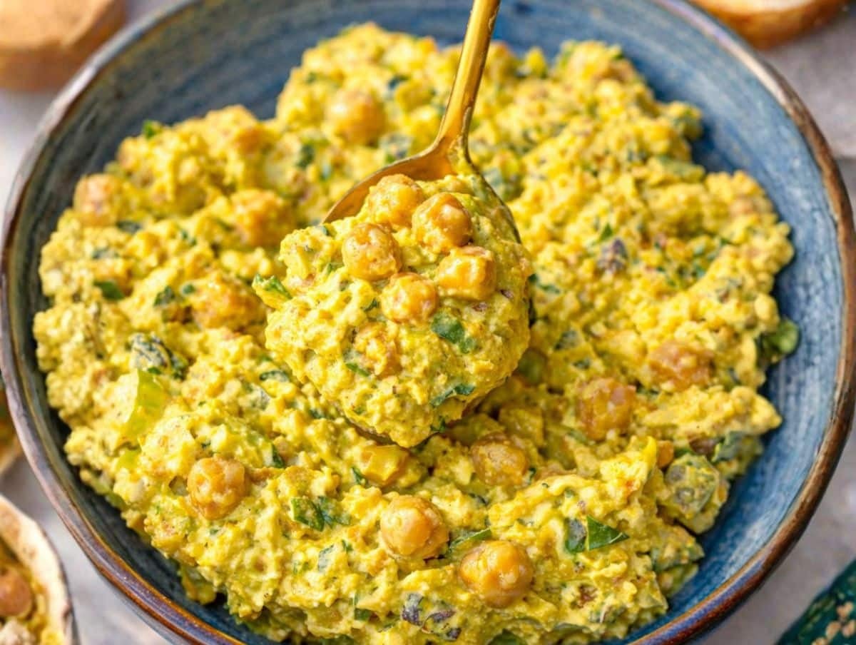 Curried chickpea salad with Greek yogurt served in a rustic bowl with spoon.