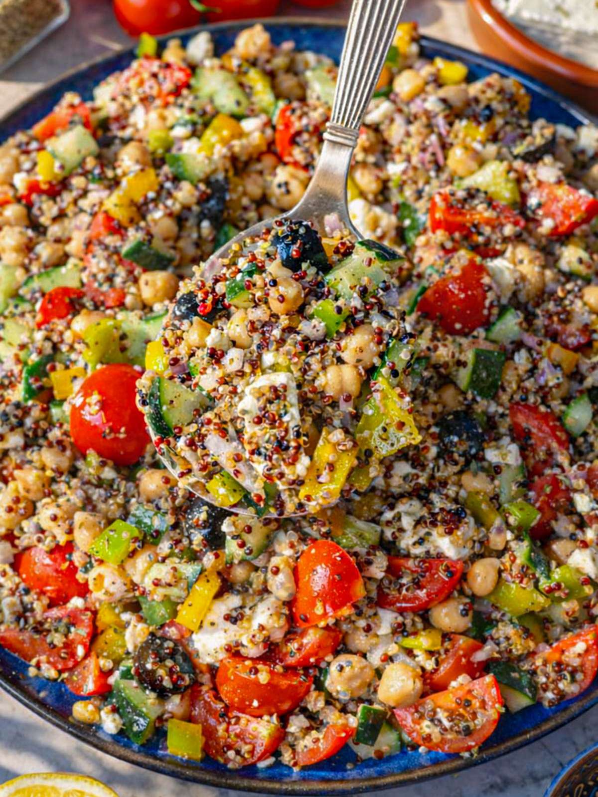 Greek quinoa salad on a large platter with quinoa chickpeas vegetables and feta.