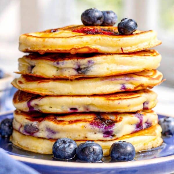 Greek yogurt blueberry pancakes stacked high on a plate in natural light.