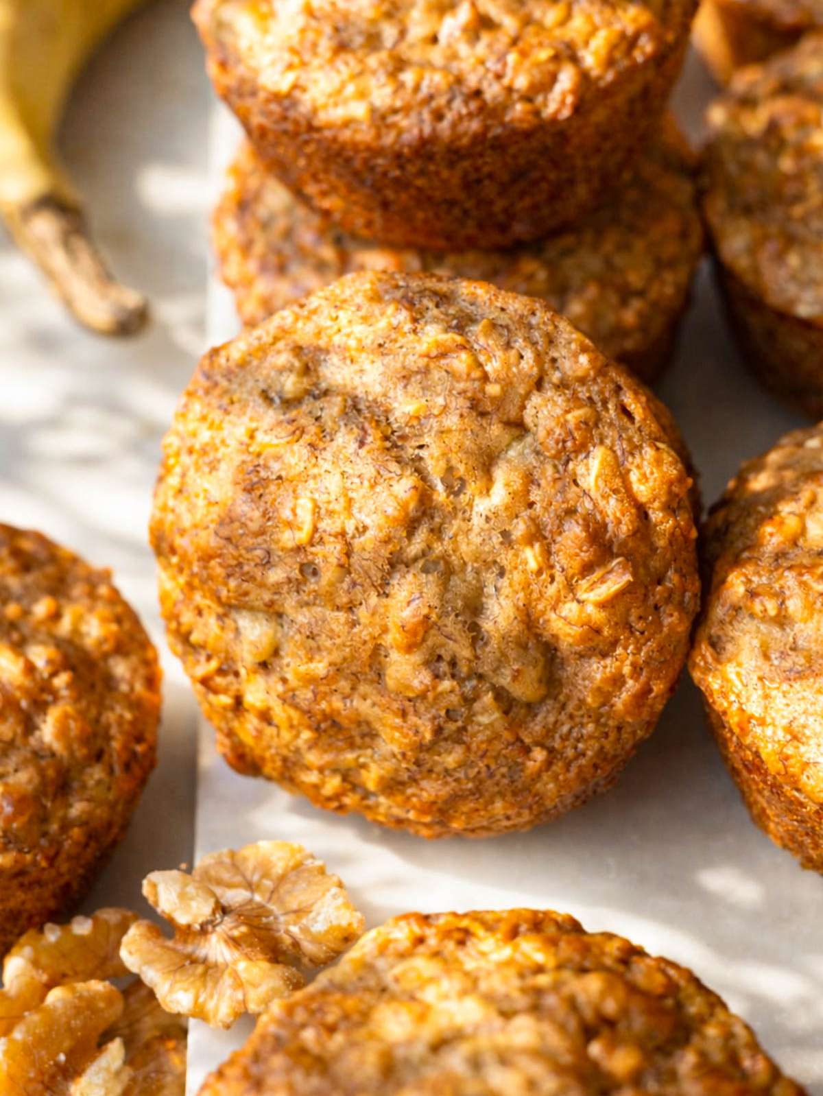 Healthy banana nut muffins on a marble surface showing golden tops and chopped walnuts.