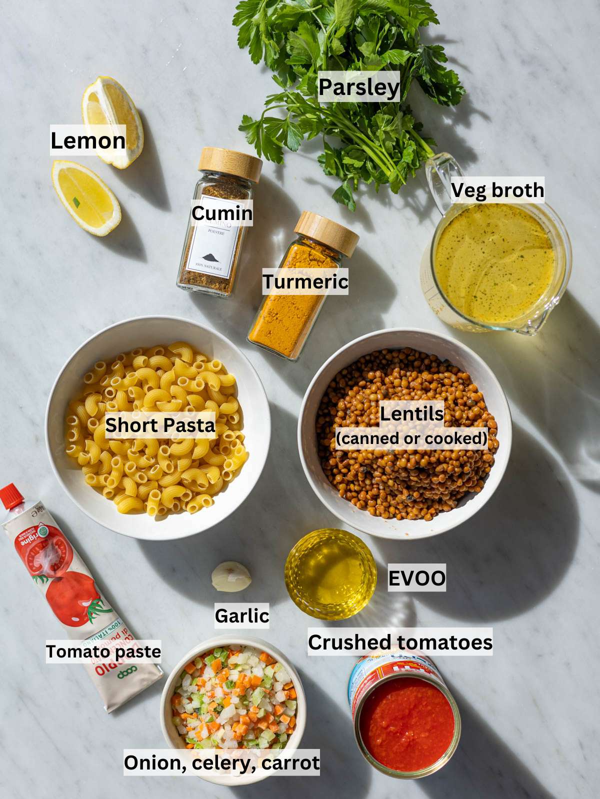 Ingredients for lentil noodle soup arranged neatly on marble kitchen table.