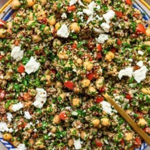 Large serving bowl of quinoa tabbouleh with chickpeas on rustic wooden table.