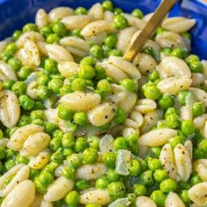 Pasta and peas served warm in a simple bowl with olive oil and Parmesan.