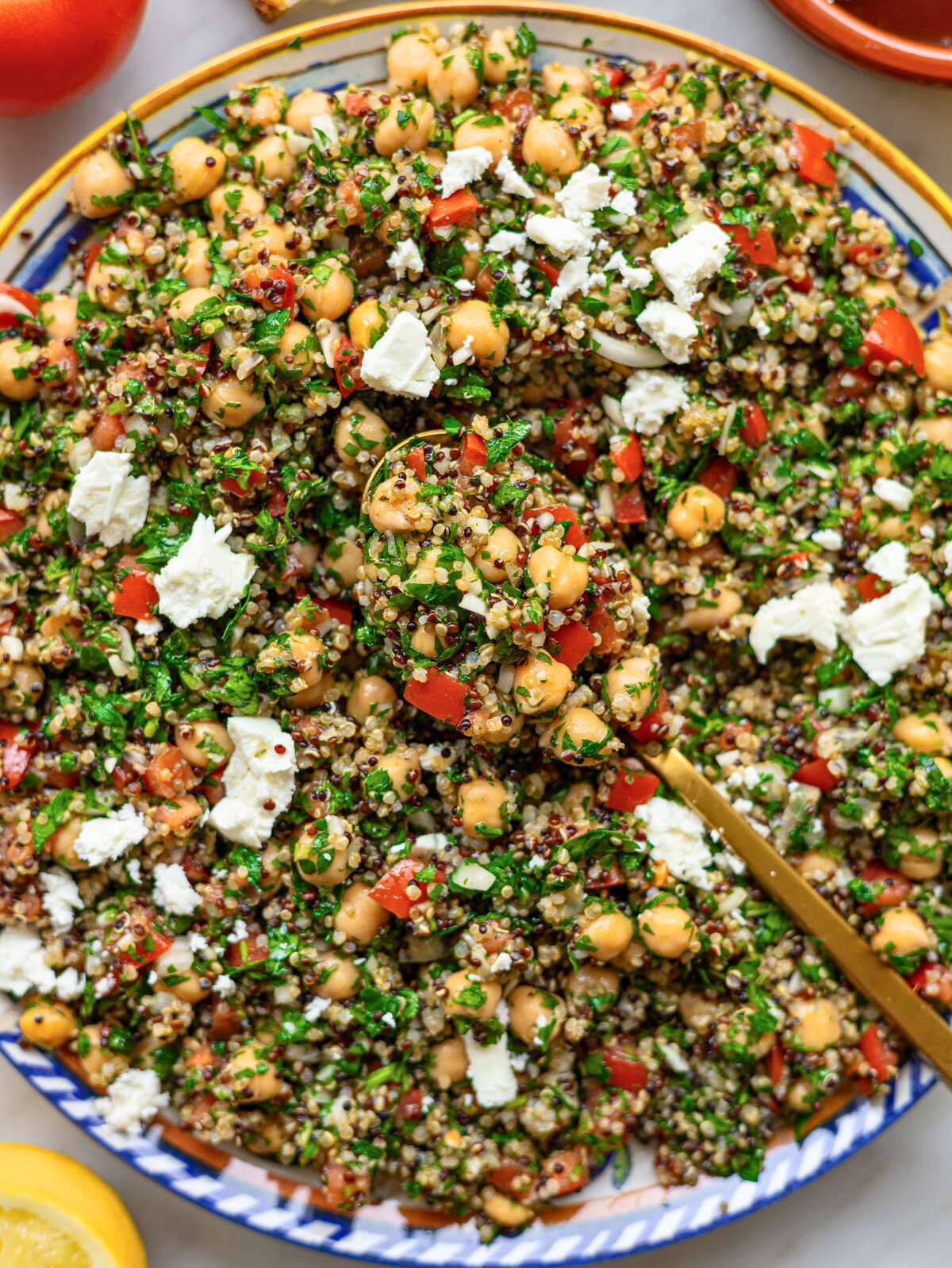Platter with quinoa tabbouleh and chickpeas topped with fresh herbs and feta.
