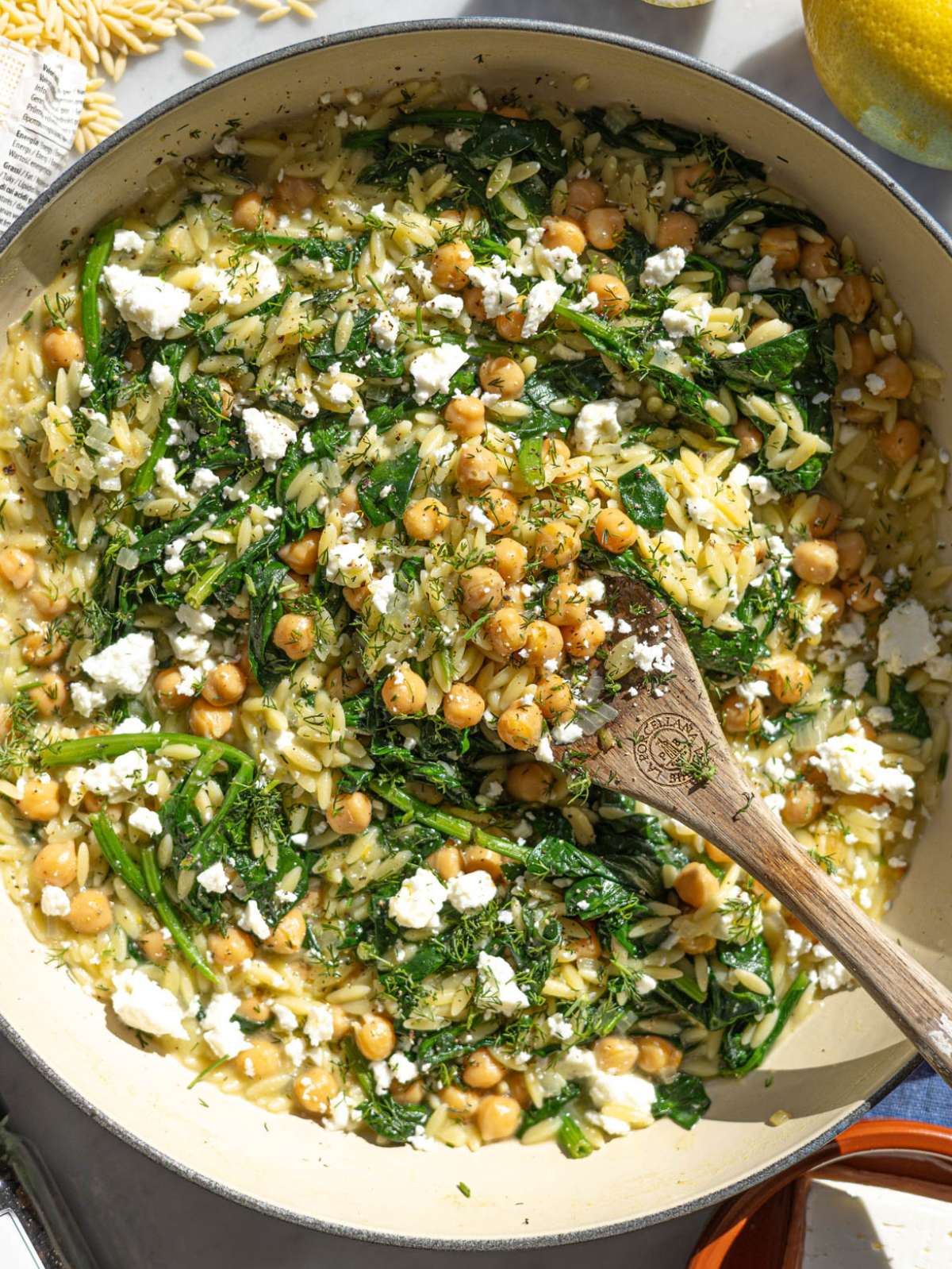 Skillet of creamy spinach orzo topped with feta and fresh dill.