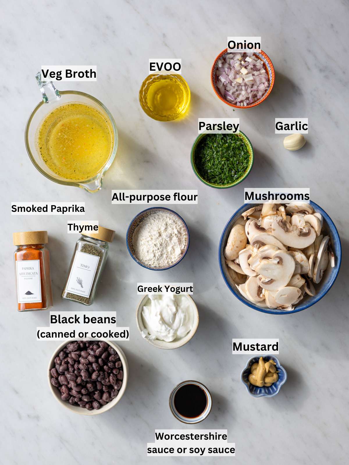 Sliced mushrooms, black beans, yogurt, broth, spices, and onion on wooden table.