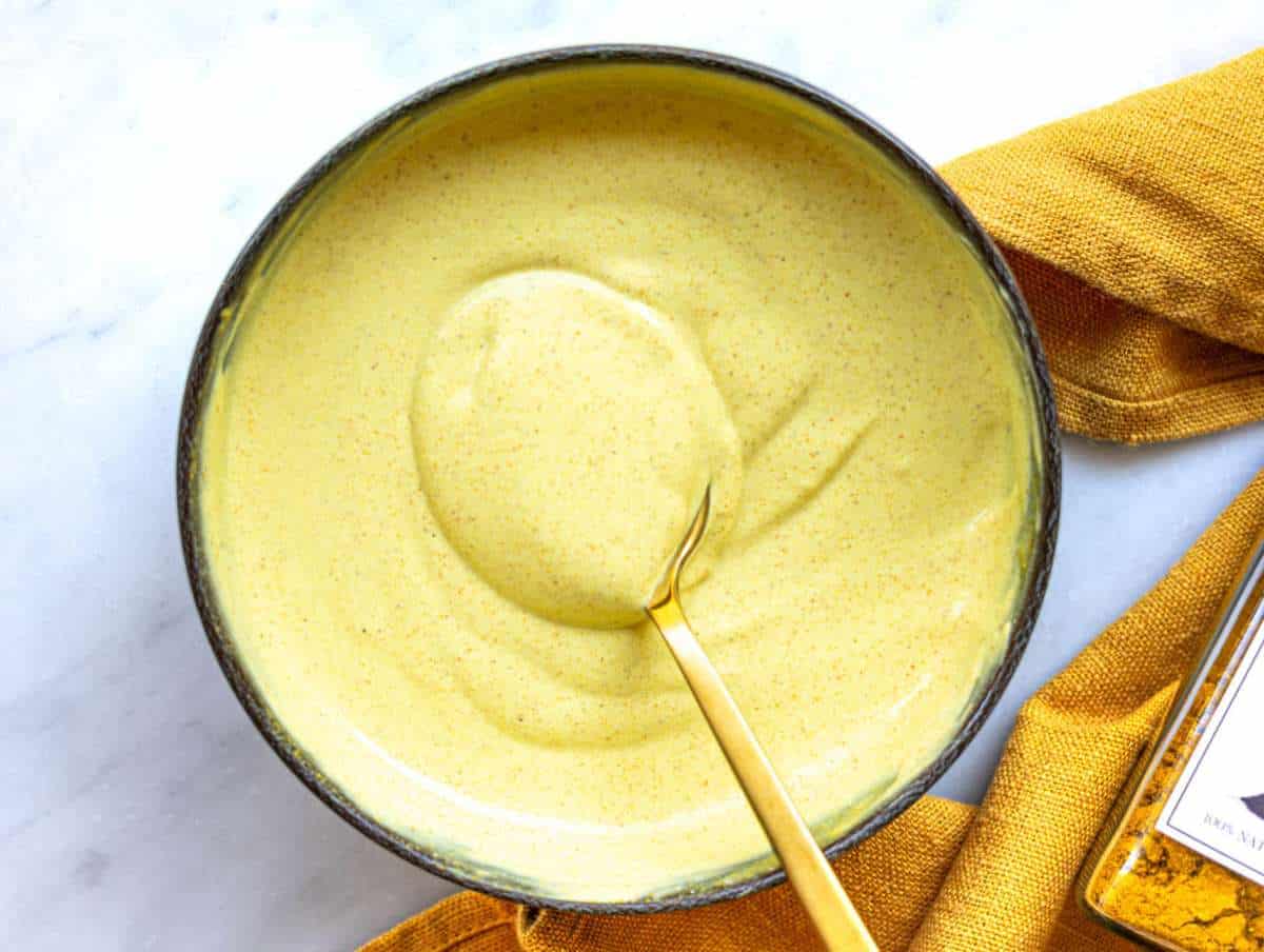 Step 1 Greek yogurt dressing with curry and mustard being whisked until smooth.