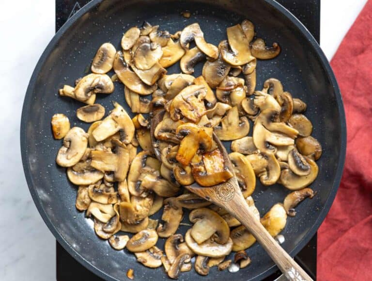 Step 1 Mushrooms browning in skillet with light golden edges.