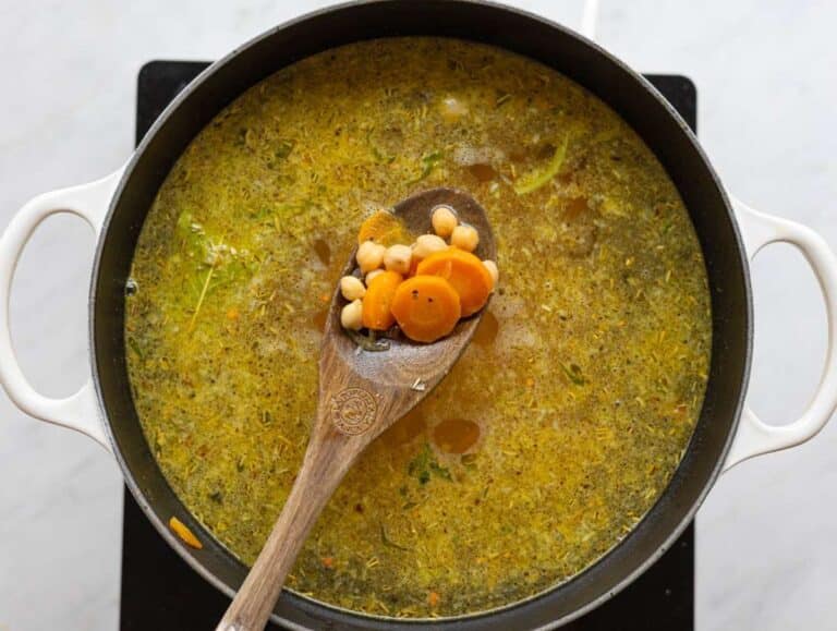 Step 2 Chickpeas and vegetable broth poured into the pot with herbs floating on the surface.