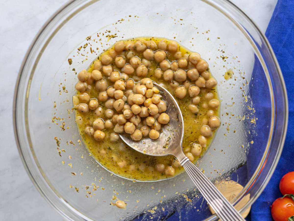 Step 2 Chickpeas coated in lemon dressing resting in a mixing bowl.