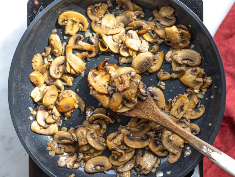 Step 2 Chopped onion and garlic cooking with mushrooms in pan.