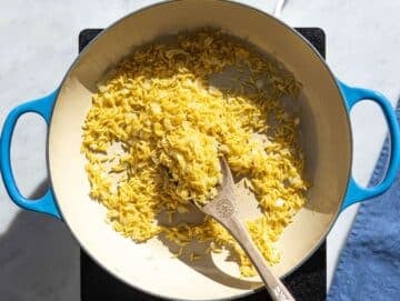 Step 2 Orzo toasting in skillet with onions and garlic.
