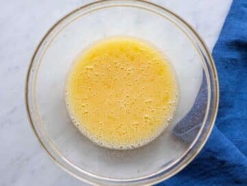 Step 2 Whisking egg, olive oil, honey, and orange juice in glass bowl.