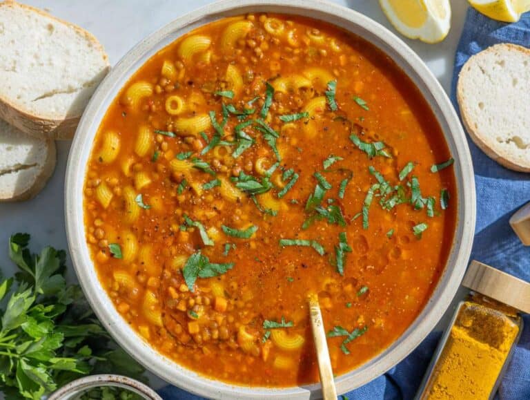Step 4 bowl of lentil noodle soup with crusty bread and lemon wedge.