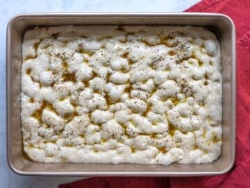 Step 6 Dimpled focaccia and filled with olive oil and black pepper before baking.