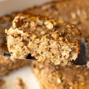 Thick slice of banana baked oatmeal on a spatula showing moist texture.