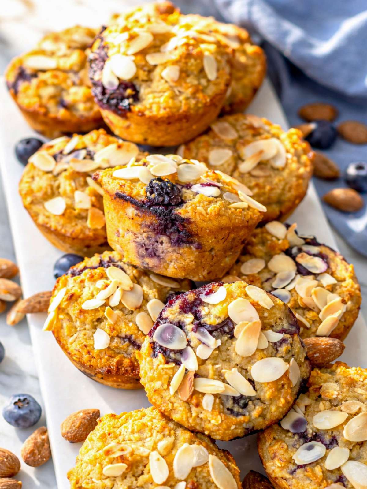 A batch of muffins cooling on a white marble counter in soft morning window light.